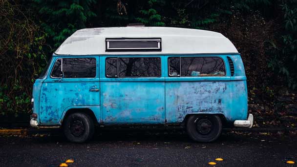 A parked old but running mini van on a street.