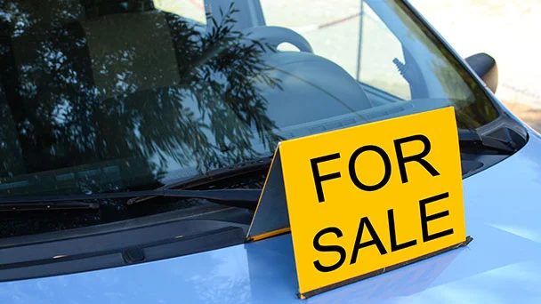 Yellow For Sale sign on blue car bonnet.