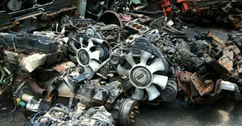 Various car parts including an engine and other items that have been stripped from old vehicles.
