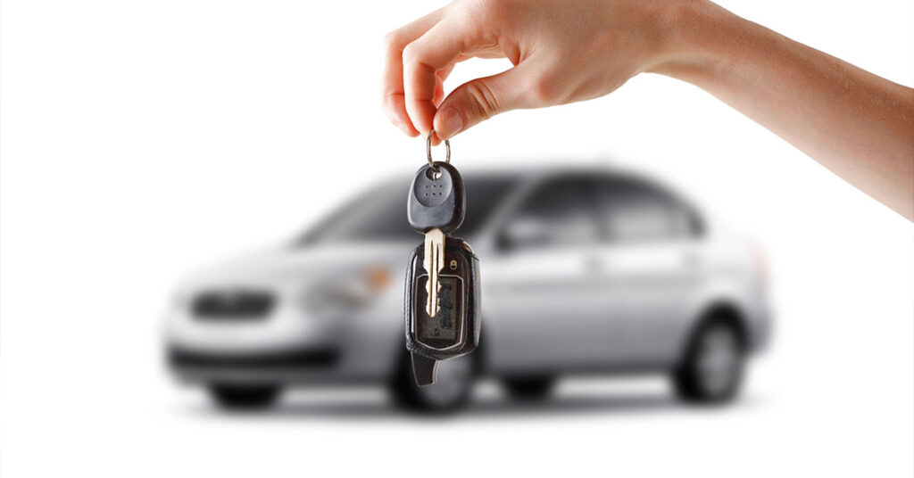 Owner holding car keys in front of car trying to find a buyer