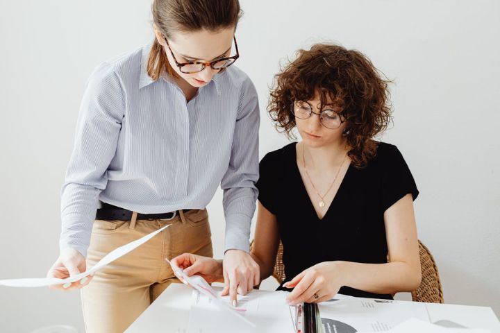 Two Women Looking at White Papers.